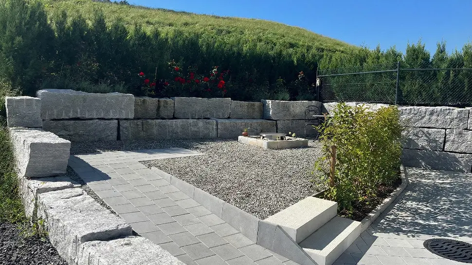 Gepflegte Außenanlage mit Natursteinmauern, Wegen und Sitzbereich