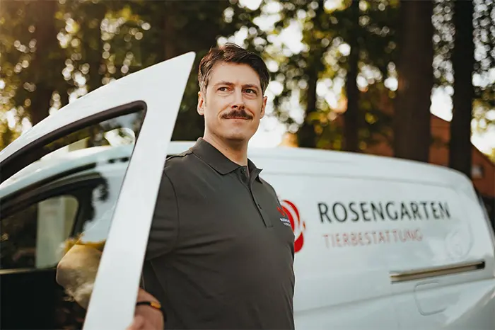 Mitarbeiter steht an einem weißen ROSENGARTEN-Fahrzeug.