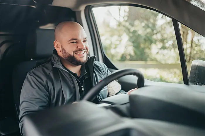 Lächelnder Mann am Steuer eines Transportfahrzeugs.