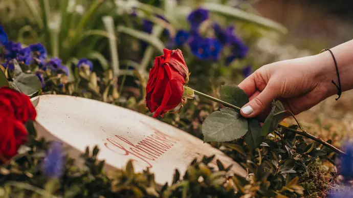 Frau legt Rose auf einem Urnengrab für ein Tier ab.