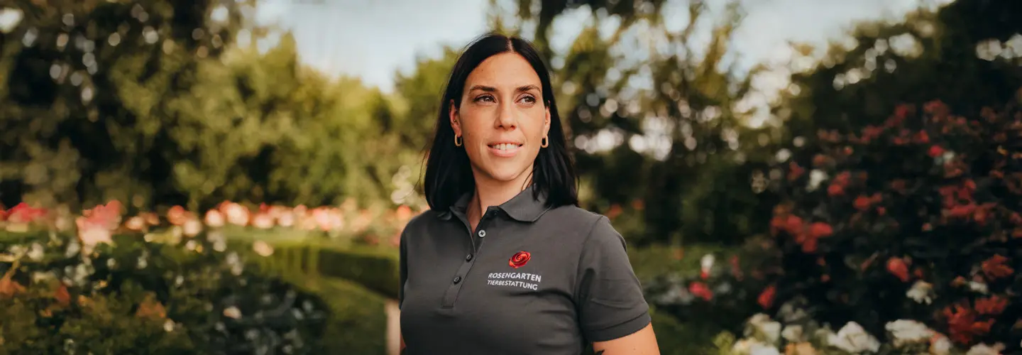 Mitarbeiterin der ROSENGARTEN-Tierbestattung steht in einem blühenden Garten.