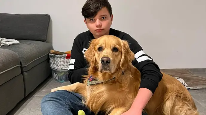 Ein Junge sitzt auf dem Boden und hält seinen treuen Golden Retriever eng an sich auf seinem Schoß
