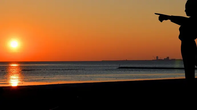 Vater und Sohn mit Hund schauen sich Sonnenuntergang an