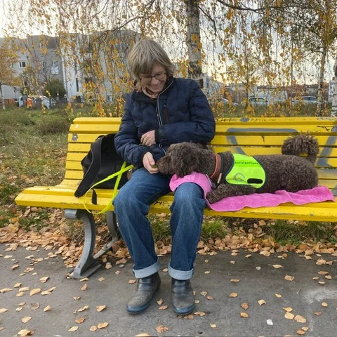 Carola und ihre Assistenzhündin Effi auf einer Parkbank – Unterstützung und Sicherheit im Alltag.