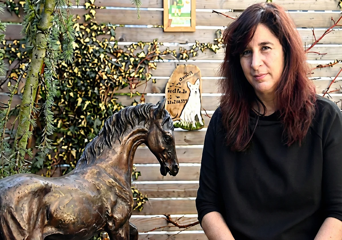 Frau sitzt im Garten neben einer Pferdeskulptur aus Metall
