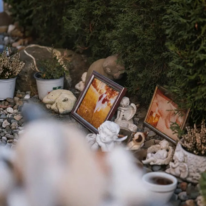 Gedenkecke im Garten mit eingerahmten Fotos, Figuren und Pflanzen
