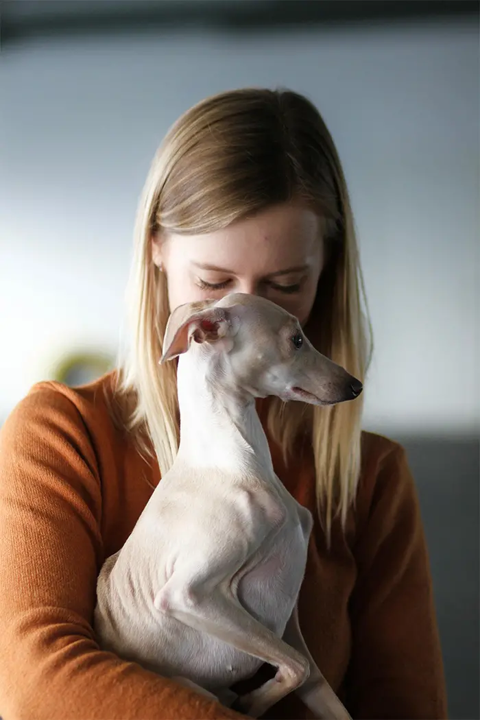 Eine Frau gibt ihrem Hund in einer Altstadt ein High-Five.