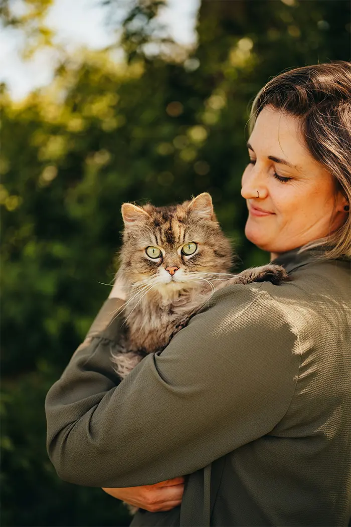 Frau hält eine flauschige Katze im Arm.