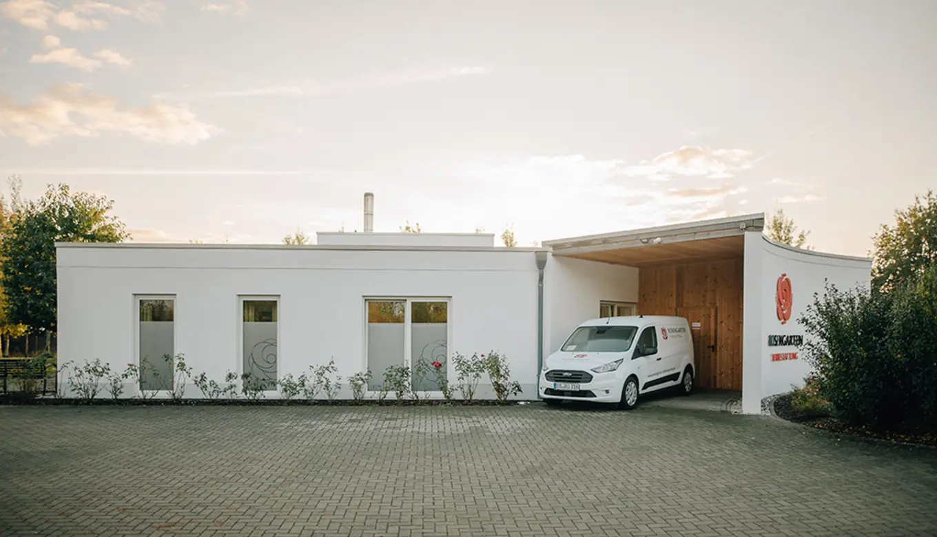Das Bild zeigt ein modernes Tierkrematorium mit dem Logo "Rosengarten" und einem gepflegten Außenbereich.